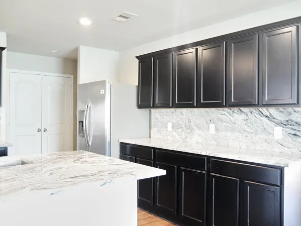 a kitchen with stainless steel appliances granite countertop wooden cabinets a refrigerator and a sink