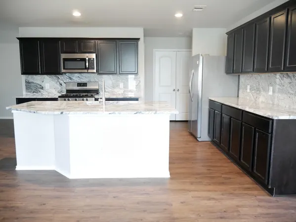 a kitchen with stainless steel appliances granite countertop a refrigerator a stove top oven a sink and dishwasher
