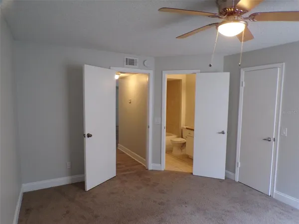 an empty room with closet and a chandelier fan