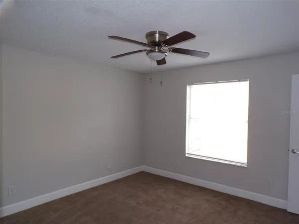 an empty room with a window and a fan
