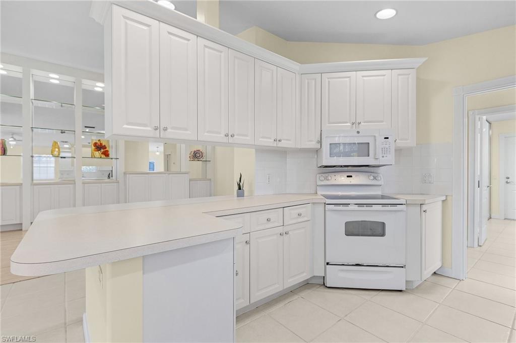 4187 St George Lane Naples, FL 34119 - Photo 6 of 27 Kitchen with kitchen peninsula, white appliances, and white cabinets