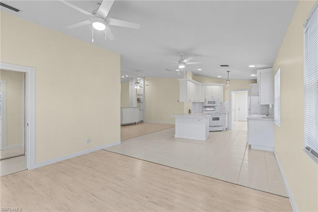 4187 St George Lane Naples, FL 34119 - Photo 9 of 27 Kitchen featuring pendant lighting, white appliances, light hardwood / wood-style flooring, a kitchen island, and white cabinetry