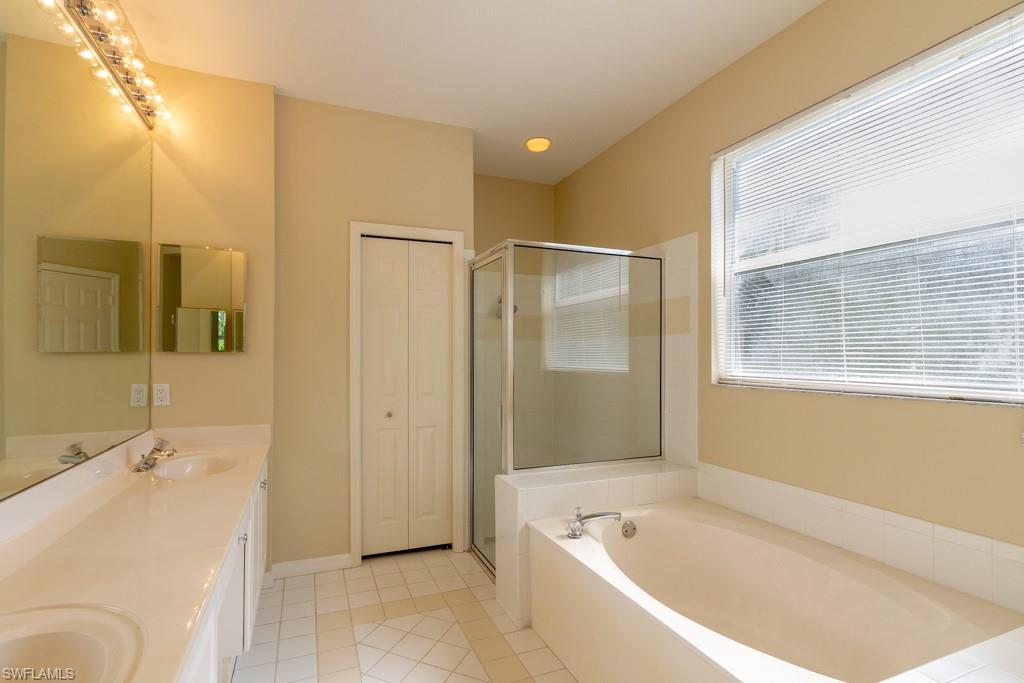 1869 Pondside Lane Naples, FL 34109 - Photo 12 of 35 a bathroom with a tub a sink and a large mirror