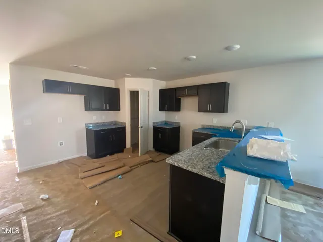 a living room with furniture a fireplace a flat screen tv and kitchen view