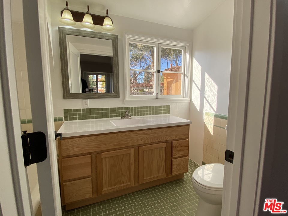 4247 9th Avenue Los Angeles, CA 90008 - Photo 38 of 45 a bathroom with a granite countertop toilet sink and a mirror