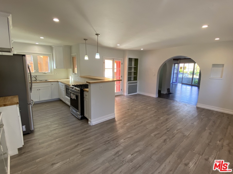 4247 9th Avenue Los Angeles, CA 90008 - Photo 4 of 45 a kitchen with stainless steel appliances granite countertop a refrigerator a sink dishwasher a stove and a dining table with wooden floor