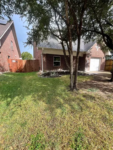 a view of a yard in front of a house with large tree