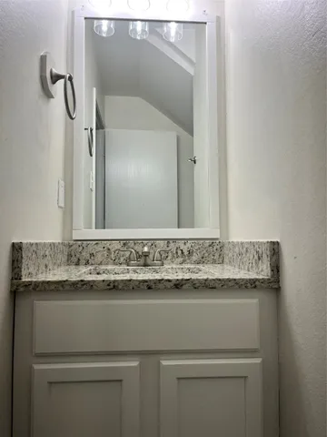 a bathroom with a granite countertop sink and a mirror