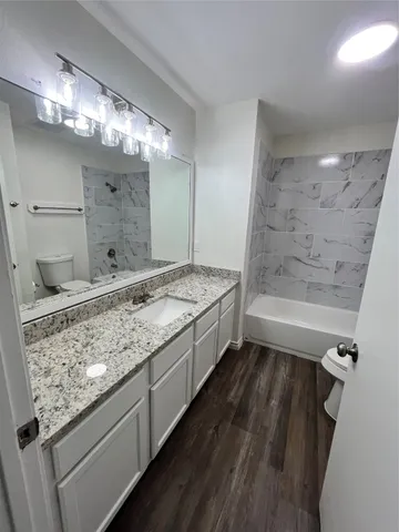 a bathroom with a granite countertop sink a toilet a mirror and shower
