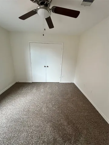 an empty room with a ceiling fan and window