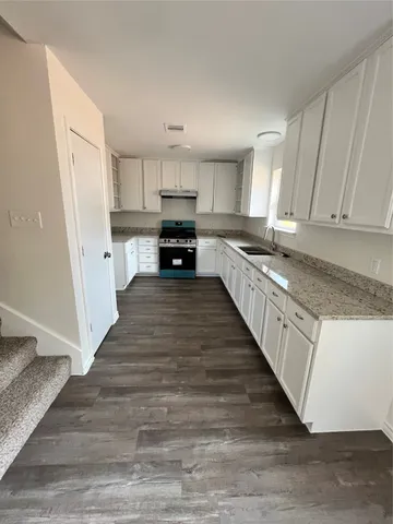 a large kitchen with cabinets wooden floor and stainless steel appliances