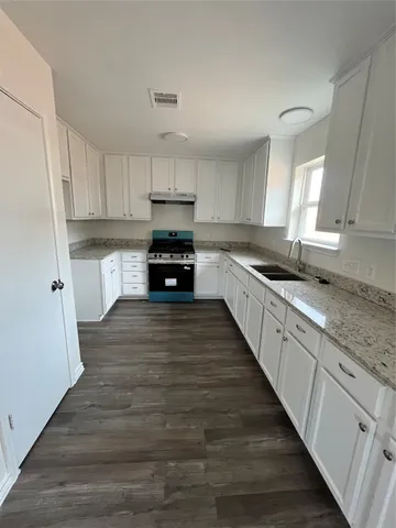 a kitchen with kitchen island granite countertop a sink cabinets and wooden floor