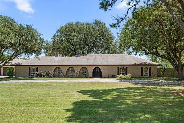 a front view of a house with a garden and trees