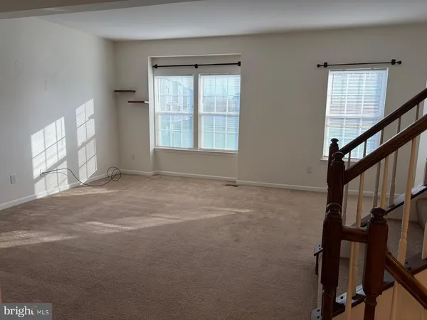 a view of an empty room with wooden floor and windows