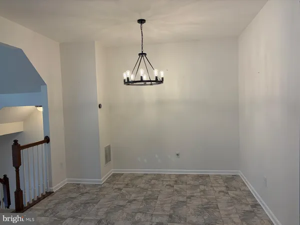 a view of a room with a hanging light and kitchen view