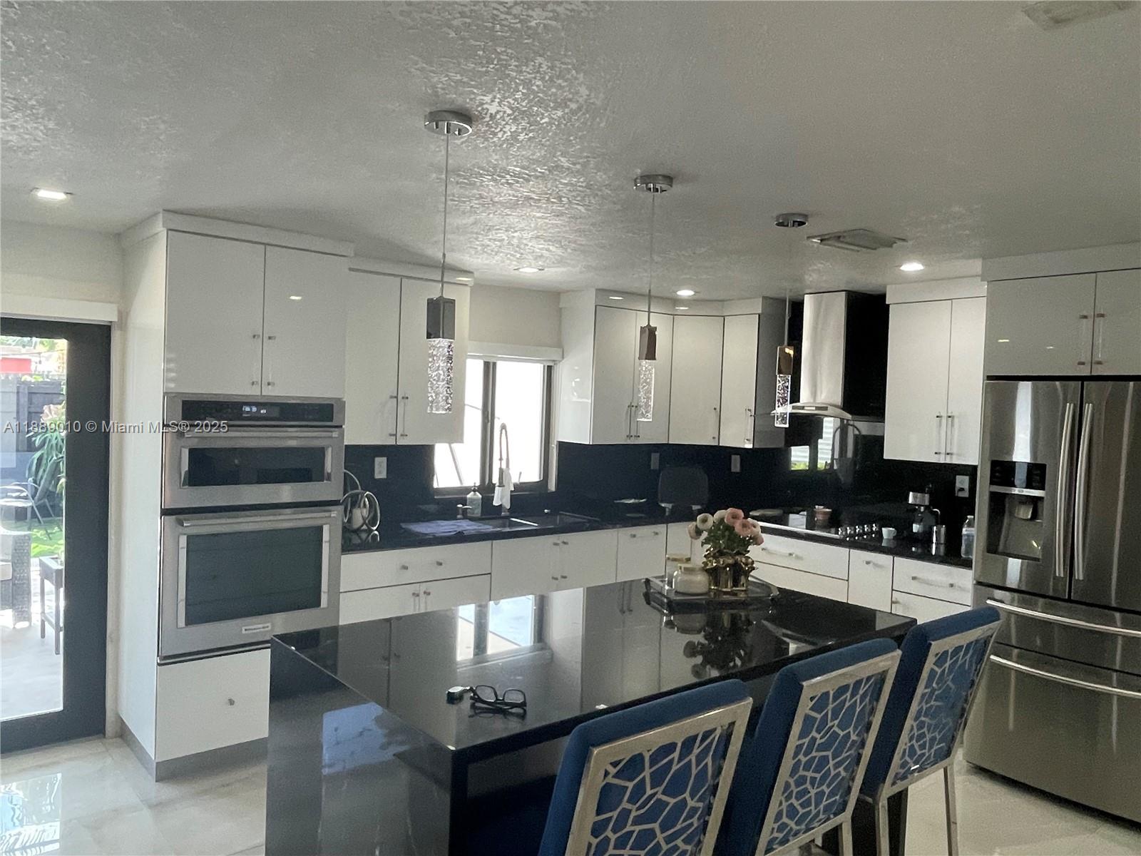 390 East 53rd Street Hialeah, FL 33013 - Photo 7 of 21 a kitchen with stainless steel appliances granite countertop a stove top oven a sink a dining table and chairs