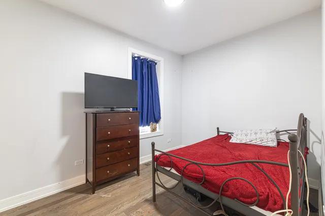 a bedroom with a bed and a flat tv screen on a dresser
