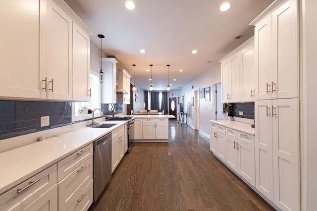 a large kitchen with stainless steel appliances lots of white cabinets and wooden floor