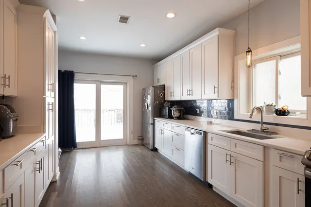 a kitchen with white cabinets and wooden floors