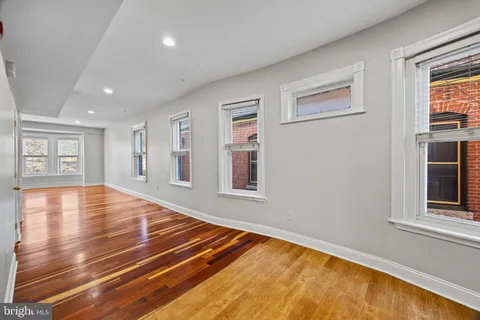 a view of an empty room with window and wooden floor
