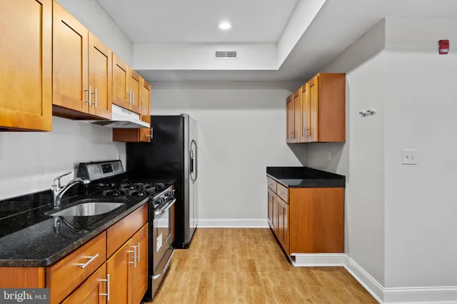 a kitchen with stainless steel appliances granite countertop a stove a sink and a refrigerator