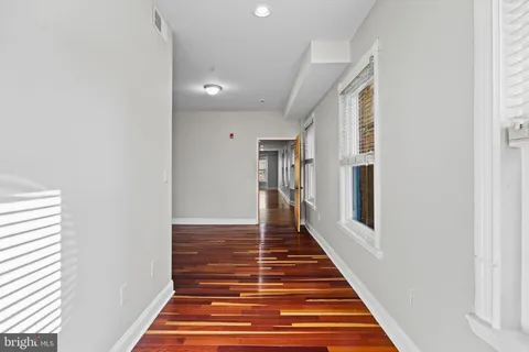 a view of a hallway with wooden floor and staircase