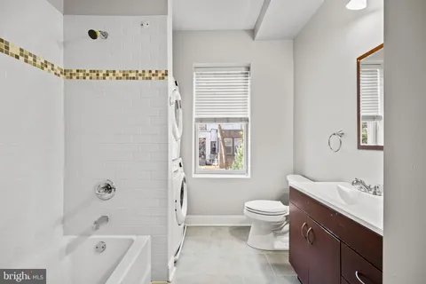 a bathroom with a bathtub shower sink vanity mirror and toilet