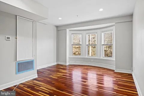 a view of an empty room with wooden floor and a window