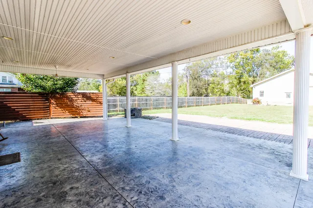 a view of an empty room with floor to ceiling windows with yard