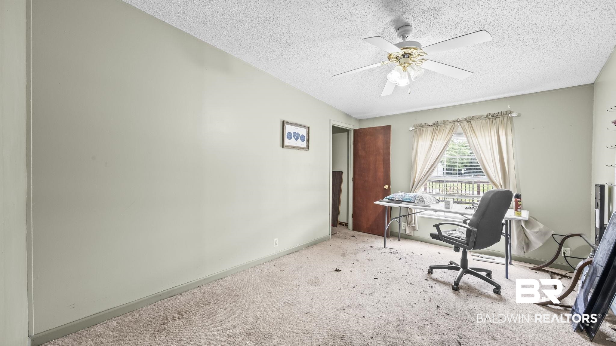 34985b Spring Road South, Unit B Stapleton, AL 36578 - Photo 10 of 31 Light-colored walls with a window featuring a white wooden railing beyond, and a ceiling fan with light fixture