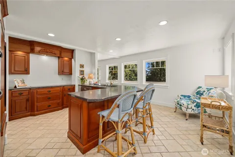 a dining hall with stainless steel appliances granite countertop a stove a sink a dining table and chairs