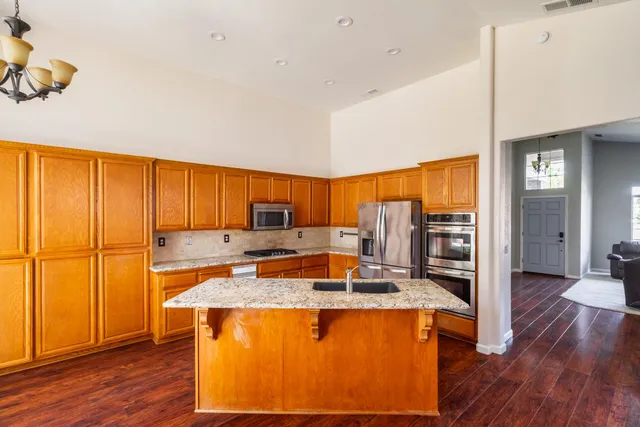 a kitchen with stainless steel appliances granite countertop a sink refrigerator and cabinets