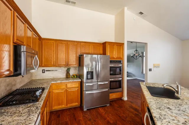 a kitchen with stainless steel appliances granite countertop a refrigerator and a sink