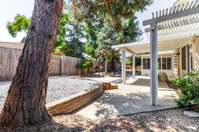 a view of a house with a small yard and large tree