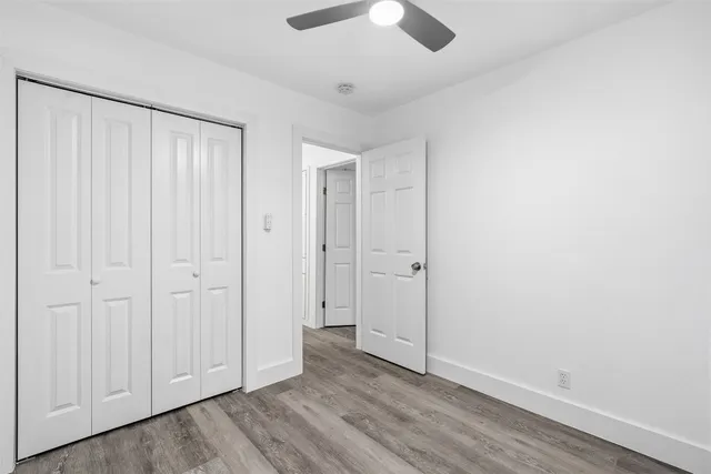 an empty room with wooden floor closet and windows