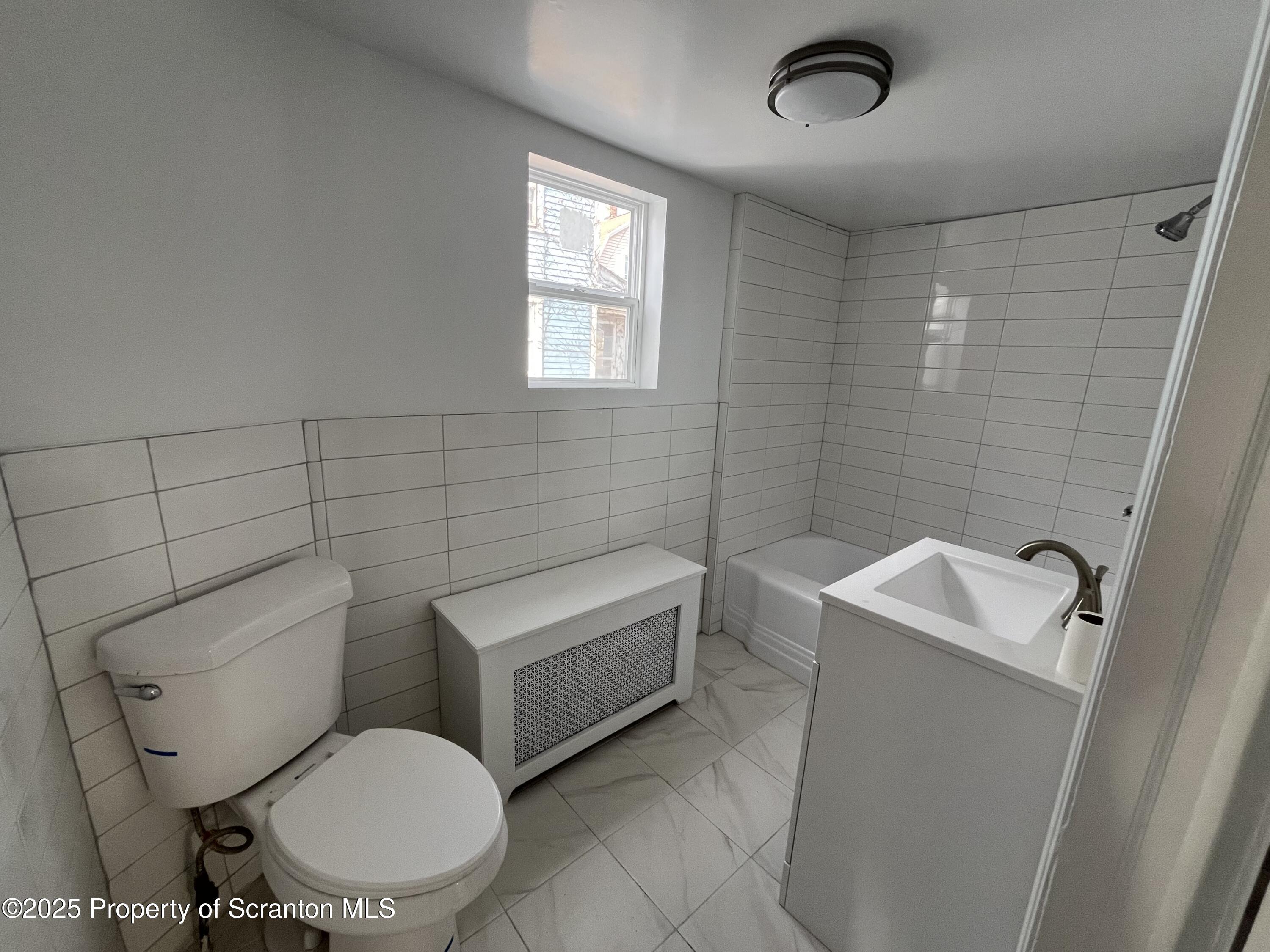 909 Battle Street Scranton, PA 18508 - Photo 7 of 13 a white toilet sitting next to a bathroom sink and tub