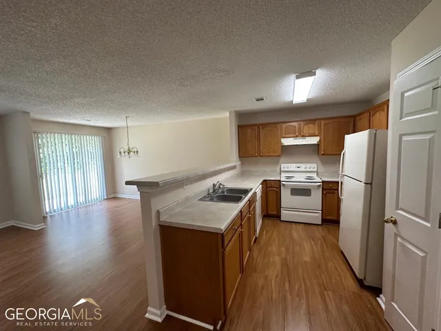 a kitchen with granite countertop a refrigerator a stove a sink dishwasher and a stove with wooden floor