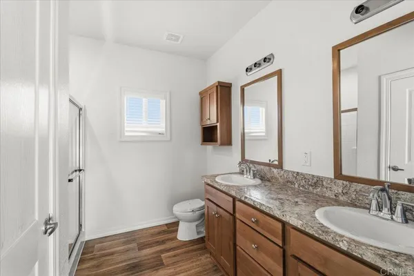 a bathroom with a granite countertop double vanity sink a mirror and a toilet