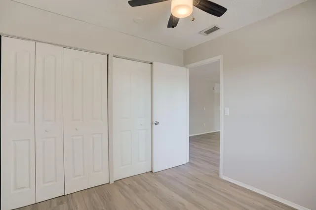 an empty room with wooden floor closet and windows