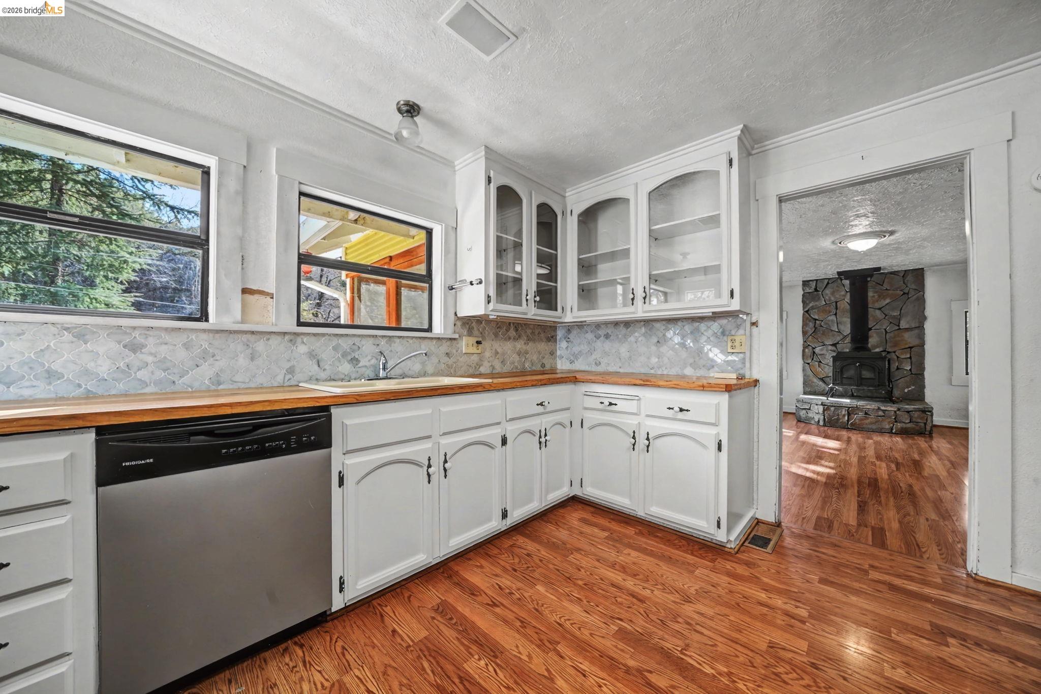 731 Dam Road Murphys, CA 95247 - Photo 11 of 60 a kitchen with wooden floors and white cabinets