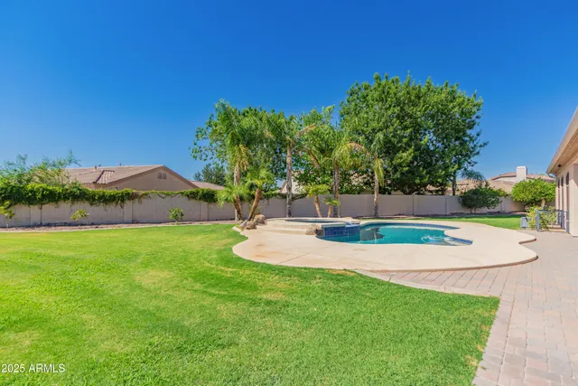 an aerial view of a house with swimming pool and large trees