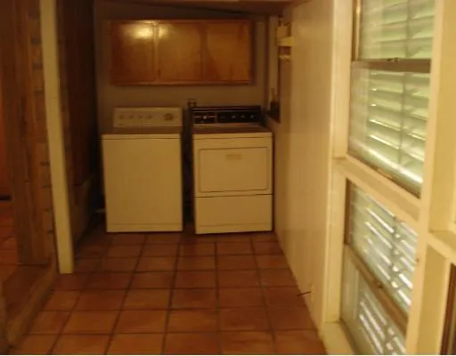 a view of a refrigerator in kitchen and an empty room with windows