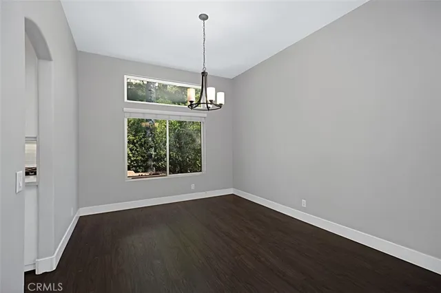 a view of a room with wooden floor chandelier and windows