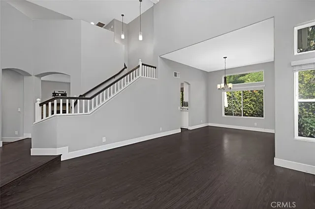 an empty room with wooden floor windows and entrance