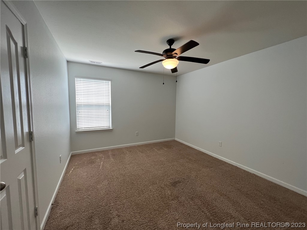 251 Botanical Court Bunnlevel, NC 28323 - Photo 13 of 20 an empty room with windows and fan chandelier fan