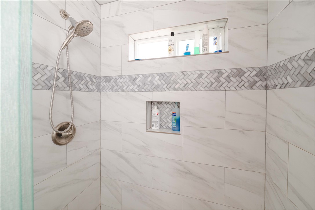 2948 Pinal Road Golden Valley, AZ 86413 - Photo 20 of 59 Shower with marble-look tile, herringbone mosaic accent, built-in niches, and brushed nickel fixtures