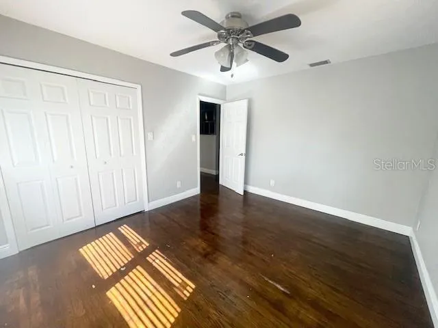 an empty room with wooden floor closet and windows