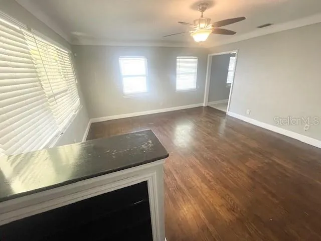 a view of an empty room and window and chandelier fan