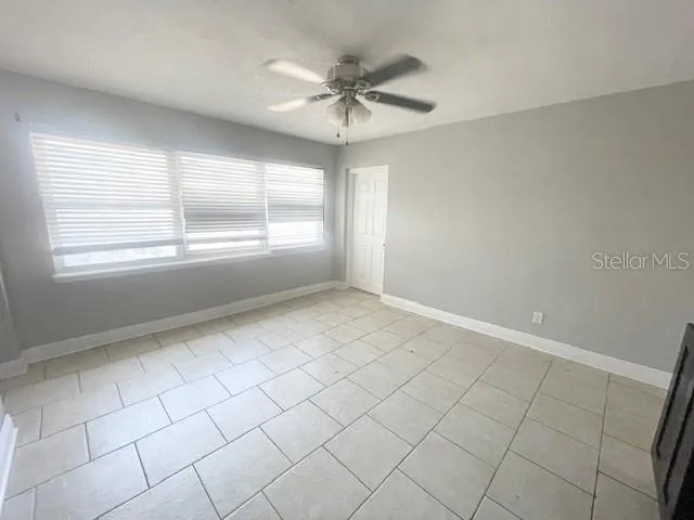 an empty room with windows and ceiling fan