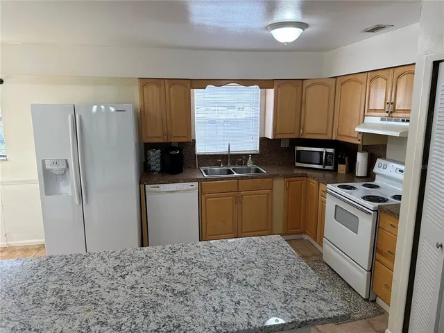 a kitchen with stainless steel appliances granite countertop a refrigerator stove and sink